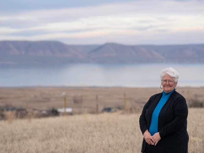 Kathi Izatt standing with hands clasped, Bear Lake in the background
